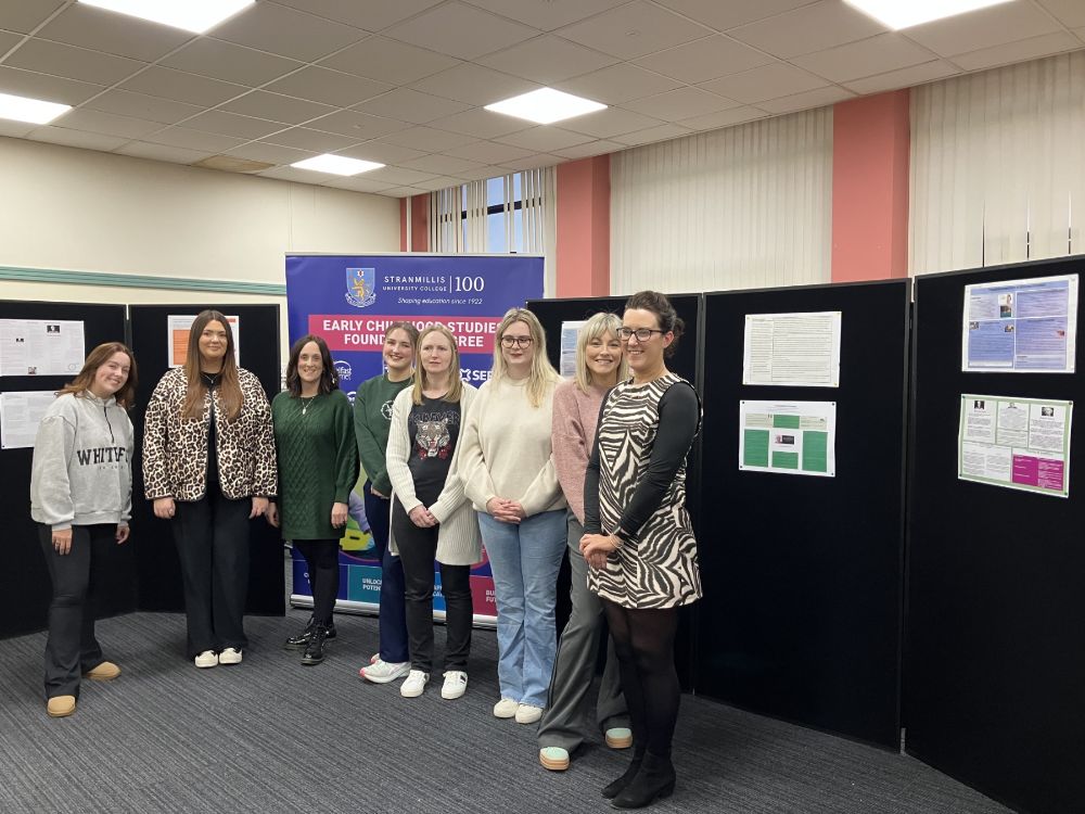 A group of students stand by the display of their academic posters 